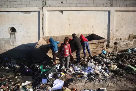 أطفال نازحون يبحثون في صندوق قمامة بدير البلح وسط قطاع غزة الأحد (أ.ف.ب).webp