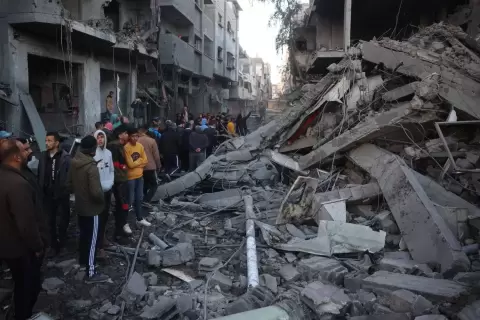 فلسطينيون يقفون بجوار أنقاض مبنى بعد غارة جوية إسرائيلية على لاجئي النصيرات وسط قطاع غزة (أ.ف.ب).webp
