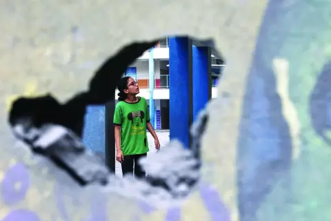فتاة فلسطينية تتفحص الأضرار بفناء مدرسة تديرها «الأونروا» في غزة (أ.ف.ب).webp