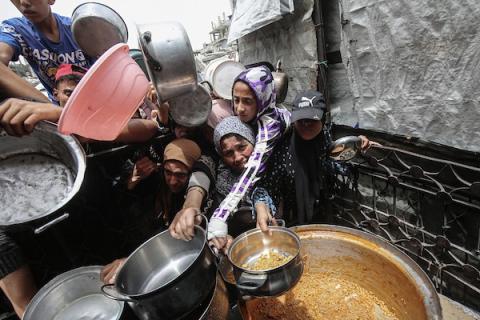 اطفال أمام احد التكيات يتصارعون للحصول على بعض الطعام