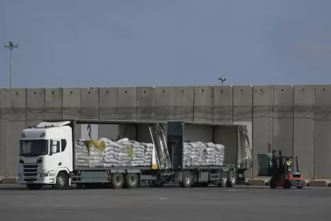 عامل يفرغ حمولة شاحنة مساعدات إنسانية لقطاع غزة في منطقة التفريغ بمعبر كرم أبو سالم (.webp