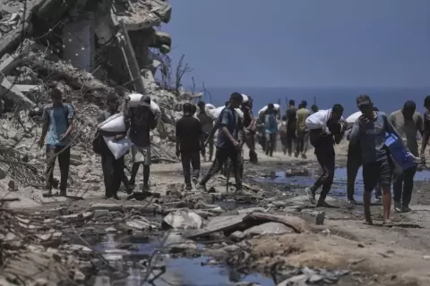غزيون يحملون ما تيسر من مساعدات غذائية.webp