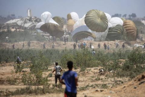فلسطينيون يهرعون إلى موقع إسقاط مساعدات جواً في النصيرات وسط قطاع غزة يوم الأربعاء.jpeg