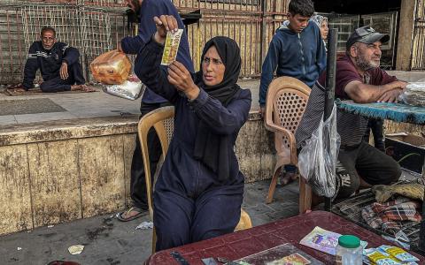 الفلسطينية منال السعيداني تُصلح أوراقًا نقدية قديمة ومهترئة في مخيم النصيرات، وسط قطاع غزة، تصوير: بلال أبو عامر