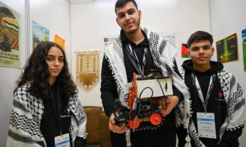 المشاركون الفلسطينيون رزان شاور (يسار) وجهاد أبو دية (يمين) ومصطفى عاصي (وسط) في أولمبياد الروبوت العالمي في سنغافورة- 28 نوفمبر 2025.jpg