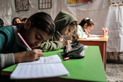 أطفال فلسطينيون نازحون يحضرون درسًا داخل خيمة تُستخدم كفصل دراسي مؤقت في ملجأ بدير البلح