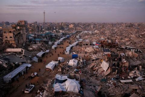 فلسطينيون يسيرون أمام الخيام الممتدة على طول الشوارع وسط أنقاض المباني المدمرة في جباليا (أ.ف.ب).jpeg