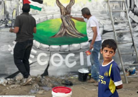 جدارية وسط أنقاض المباني المدمرة في خان يونس، جنوب قطاع غزة، تصور شجرة زيتون - رمز السلام - قبل عرضها في قمة المناخ في البرازيل، كرسالة من غزة إلى العالم عن الصمود والأمل.  تصوير: طارق محمد