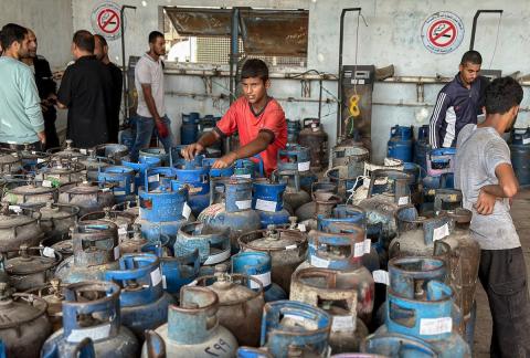 عمال يتعاملون مع أسطوانات الغاز في محطة تعبئة في النصيرات، وسط قطاع غزة، في وقت يعاني فيه القطاع من أزمة حادة في إمدادات الوقود.تصوير: بلال أبو عامر