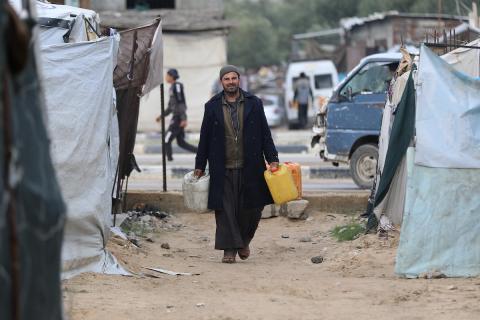 يتجمع الفلسطينيون لتلقي مياه الشرب مجانًا في مخيم البريج للاجئين، في ظل تفاقم أزمة نقص المياه وتدهور البنية التحتية، 21 ديسمبر/كانون الأول 2025. صورة: رمزي أبو عامر
