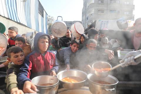 يتلقى الفلسطينيون، بمن فيهم الأطفال، الذين يعانون من صعوبة الحصول على الغذاء بسبب الهجمات الإسرائيلية المستمرة، وجبات ساخنة توزعها إحدى الجمعيات الخيرية في مخيم النصيرات للاجئين وسط قطاع غزة، 5 يناير/كانون الثاني 2026. تصوير: أحمد إبراهيم