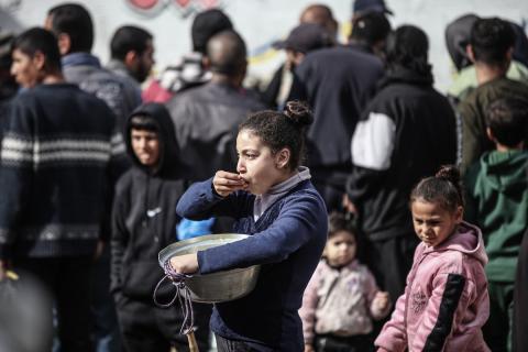 أطفال فلسطينيون ينتظرون وجبة ساخنة، توزعها إحدى المنظمات الخيرية، في ظل استمرار أزمة الغذاء بسبب محدودية المساعدات الإنسانية في مخيم النصيرات للاجئين وسط قطاع غزة، في 10 يناير/كانون الثاني 2026. صورة: معز صالحي