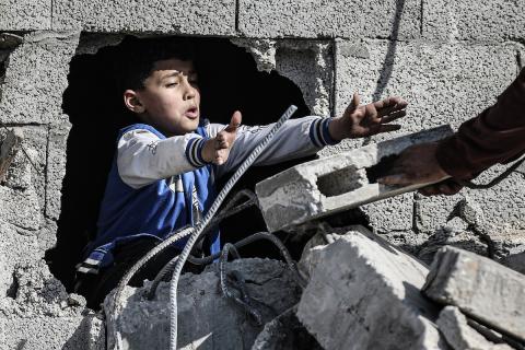 فلسطينيون يتفقدون منزلاً (تضرر سابقاً جراء غارة جوية إسرائيلية) انهار على سكانه، ما أسفر عن وفاة رجل ونجله الصغير في مخيم المغازي للاجئين وسط قطاع غزة، 5 يناير/كانون الثاني 2026. صورة: رمزي أبو عامر