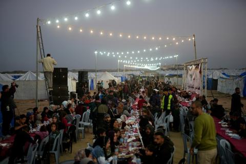 يتجمع فلسطينيون نازحون لتناول وجبة الإفطار، وهي وجبة كسر الصيام، خلال شهر رمضان المبارك في مخيم خيام يؤويهم، بحي الزهراء وسط قطاع غزة، يوم السبت 21 فبراير/شباط 2026. تصوير: عمر أشتوي