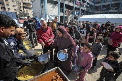 فلسطينيون بينهم أطفال ونساء يتلقون مساعدات غذائية وزعتها منظمات خيرية في أحد مراكز الإيواء بمدينة غزة، وسط أزمة غذائية مستمرة ناجمة عن محدودية المساعدات الإنسانية والظروف الإنسانية المتردية التي يواجهها النازحون، ١٢ فبراير/شباط ٢٠٢٦. تصوير: عمر أشتوي