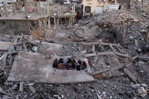 عائلة فلسطينية تتناول إفطارها خلال شهر رمضان على سطح منزلها الذي دمره قصف جوي إسرائيلي خلال حرب غزة في 27 فبراير/شباط 2026. يواجه النازحون ظروفًا معيشية بالغة الصعوبة، ونقصًا في الاحتياجات الأساسية، ونقصًا حادًا في المساعدات الإنسانية. صورة: عمر أشتوي