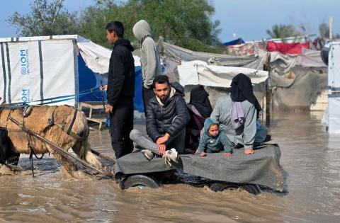 يحاول الفلسطينيون التنقل بعد أن غمرت مياه الأمطار الشوارع وخيام النازحين في خان يونس، جنوب قطاع غزة، في 24 فبراير/شباط 2026. وقد دُمرت البنية التحتية في قطاع غزة على نطاق واسع جراء الحرب والهجمات الإسرائيلية. (صورة: طارق محمد)