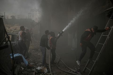 طواقم الدفاع المدني ومتطوعون من المواطنين أثناء محاولة إخماد حريق اندلع في مستودع تابع لمنظمة إغاثة في حي الرمال، غرب مدينة غزة، في 13 فبراير/شباط 2026. صورة: عمر أشتوي
