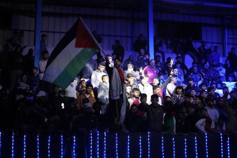 لاعبون فلسطينيون من فريقي النصيرات ورفح يتنافسون خلال مباراة كرة قدم على ملعب نادي خدمات النصيرات، ضمن بطولة غزة الرمضانية، بحضور حشد جماهيري كبير، في مخيم النصيرات بوسط قطاع غزة، بتاريخ 21 فبراير/شباط 2026. تصوير: معز صالحي / apaimages