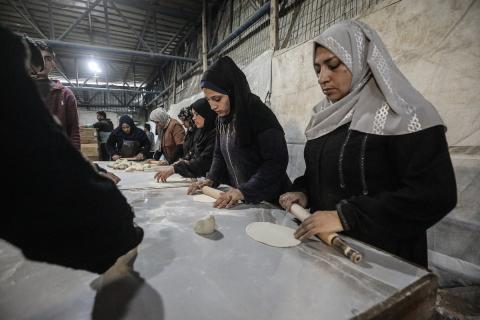 نساء فلسطينيات، زوجات شهداء الحرب، يُجهّزن الخبز لتوزيعه على العائلات النازحة والمحتاجة في مخيم البريج للاجئين وسط قطاع غزة خلال شهر رمضان، في مشهد يُجسّد روح التضامن والصمود في ظلّ الظروف الإنسانية الصعبة، فبراير/شباط 2026. تصوير: معز صالحي