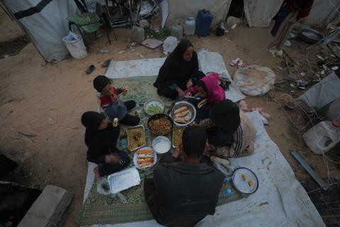 عائلة فلسطينية كفيفة تتناول وجبة الإفطار خارج خيمتها في مخيم بوسط قطاع غزة خلال شهر رمضان