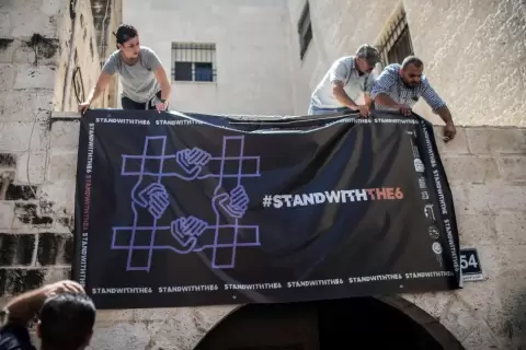 نشطاء يعلّقون لافتة تضامنا مع منظمات مجتمع مدني فلسطينية محظورة.webp