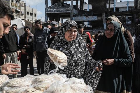 نساء فلسطينيات، زوجات شهداء الحرب، يُجهّزن الخبز لتوزيعه على العائلات النازحة والمحتاجة في مخيم البريج للاجئين وسط قطاع غزة خلال شهر رمضان، في مشهد يُجسّد روح التضامن والصمود في ظلّ الظروف الإنسانية الصعبة، فبراير/شباط 2026. تصوير: معز صالحي