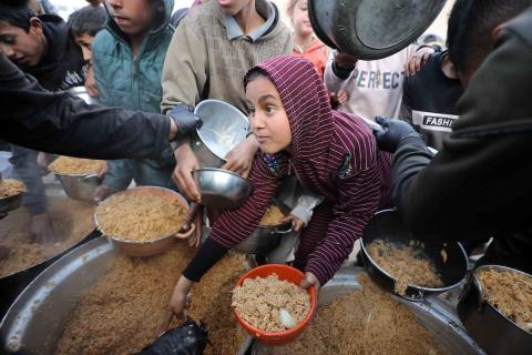 تجمع فلسطينيون نازحون، بينهم أطفال ونساء، حاملين أوعية طعام لتلقي وجبات ساخنة وزعتها جمعيات خيرية قبل الإفطار في مدينة غزة في 27 فبراير/شباط 2026.صورة: عمر أشتوي
