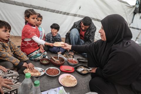 عائلة فلسطينية نازحة تتناول فطورها خلال شهر رمضان داخل خيمة متداعية في مخيم النصيرات للاجئين وسط قطاع غزة. تواجه العائلات النازحة ظروفًا معيشية قاسية نتيجة الحرب، مع انعدام الدخل ونقص حاد في المساعدات الإنسانية، 26 فبراير/شباط 2026. تصوير: معز صالحي