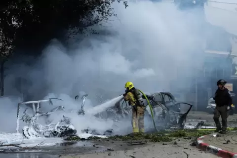 محاولة إخماد حريق اندلع في موقع سقوط شظايا صاروخ إيراني في تل أبيب (غيتي).webp