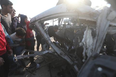 يتفقد فلسطينيون موقع هجوم إسرائيلي على سيارة شرطة قرب مدخل بلدة الزويدة وسط قطاع غزة، في 15 مارس/آذار 2026