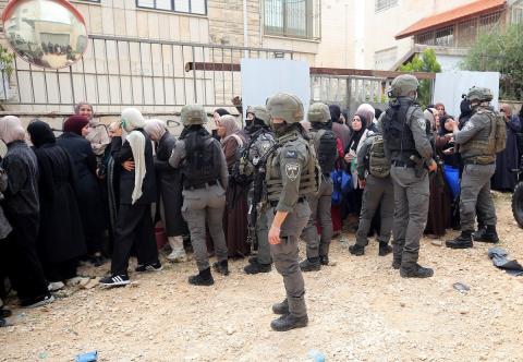 عائلات فلسطينية تنتظر عند نقطة تفتيش تابعة للجيش الإسرائيلي عند مدخل مخيم جنين للاجئين، قرب مدينة جنين في الضفة الغربية، لاستعادة ممتلكاتها من منازلها، 13 أبريل/نيسان 2026. صورة: محمد ناصر