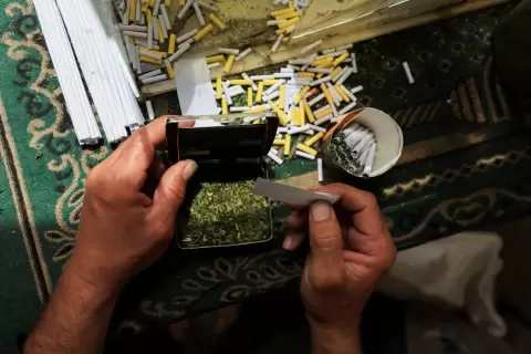 بائع فلسطيني يبيع سجائر مصنوعة من أوراق الملوخية المجففة كبديل للتبغ (رويترز).webp