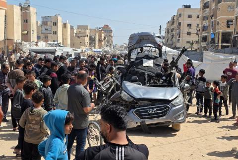 تُظهر الصورة فلسطينيين يتفقدون آثار غارة إسرائيلية استهدفت مركبة في خان يونس، جنوب قطاع غزة، حيث تحولت المركبة إلى حطام، فيما واصل الأهالي التجمع في المكان وسط حالة من الصدمة والغضب، 10 أيار/ مايو 2026.(صورة: طارق محمد)