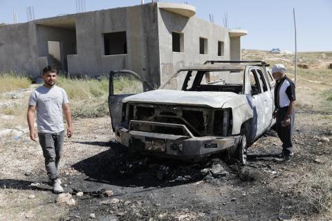 يتفقد فلسطينيون مركبةً تضررت بعد أن أضرم فيها مستوطنون إسرائيليون النار في وادي الرحيم قرب بلدة يطا، جنوب الخليل في الضفة الغربية، في الأول من مايو/أيار 2026.(صورة: مأمون وزواز)