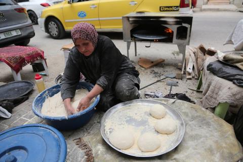 امرأة فلسطينية تُعدّ الخبز على نار الحطب في شارع رئيسي بنابلس شمال الضفة الغربية، 2 مايو/أيار 2026، خلال معرض ملح الأرض  للتراث الفلسطيني (تصوير: محمد ناصر)