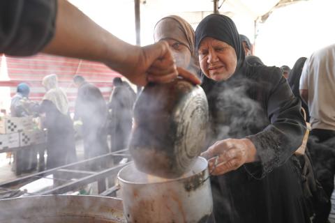 فلسطينيون نازحون، بينهم نساء وأطفال، يتجمعون لتلقي وجبات طعام من مطبخ خيري في مخيم النصيرات للاجئين وسط قطاع غزة، في 21 مايو/أيار 2026.  الصورة: رمزي أبو عامر.