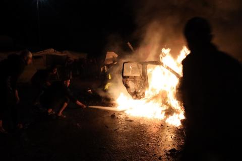 فلسطينيون يعملون على إخماد حريق اندلع في سيارة استُهدفت بغارة إسرائيلية في حي الرمال بمدينة غزة، الجمعة 15 مايو/أيار 2026. صورة: عمر أشتوي.