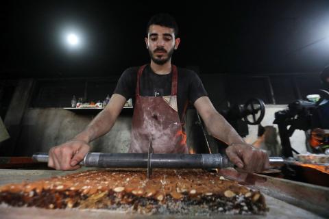 عمال فلسطينيون ينتجون حلوى “الحلقوم” التقليدية داخل مصنع متضرر في حي الدرج شرق مدينة غزة، قبيل عيد الأضحى المبارك، في 24 أيار/مايو 2026، بعد استئناف العمل بإمكانيات محدودة جراء أضرار الحرب وتراجع القدرة الشرائية للسكان. تصوير: بلال أسامة