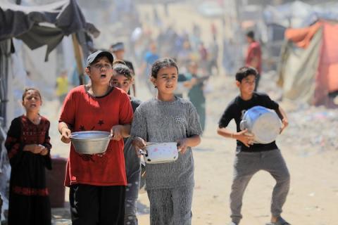 أطفال نازحون يحملون أوعية فارغة بانتظار وجبة مجانية في شرق غزة، 17 حزيران/يونيو 2026. تصوير: بلال أسامة.