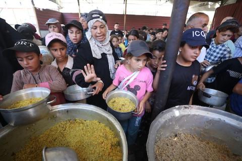 فلسطينيون نازحون، بينهم نساء وأطفال، يتجمعون للحصول على وجبات ساخنة وزّعها مطبخ خيري في مخيم النصيرات، في 13 يونيو/حزيران 2026.تصوير: حسن الجديدي