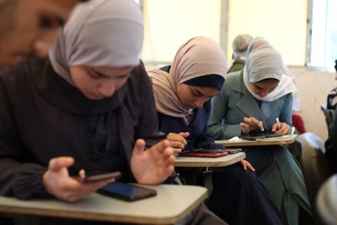 طلبة فلسطينيون يؤدون امتحان “التوجيهي” في قاعة امتحانية بقطاع غزة، رغم الأزمة الإنسانية وانقطاع الكهرباء وصعوبة الوصول إلى بيئة تعليمية مستقرة. صورة: حسن الجدي.