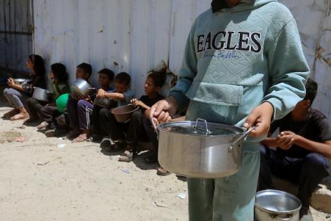 تجمّع فلسطينيون نازحون، بينهم نساء وأطفال، لتلقّي وجبات ساخنة وزّعها مطبخ خيري في غرب مدينة غزة، في 3 يونيو/حزيران 2026.   (صورة: بلال أسامة)