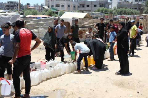 في 28 يونيو/حزيران 2026، جمع فلسطينيون نازحون المياه من شاحنة توزيع مياه مجانية في مخيم النصيرات، وسط قطاع غزة. صورة: حسن الجدي