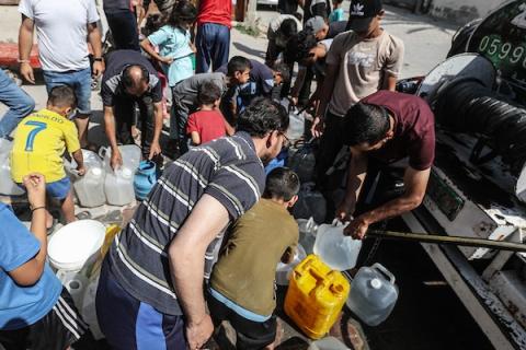 فلسطينيون نازحون ينتظرون دورهم للحصول على مياه من شاحنة توزيع متنقلة في مخيم البريج وسط قطاع غزة، تصوير: معز صالحي