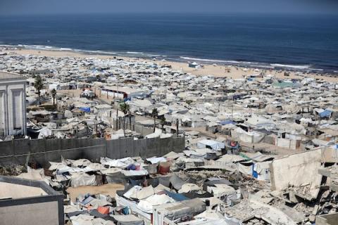 خيام تؤوي نازحين فلسطينيين على ساحل مدينة غزة وبين مبانٍ متضررة جراء الحرب، في 10 أغسطس/آب 2026. تصوير: بلال أسامة.