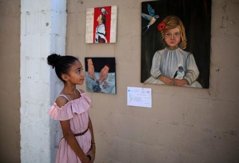 حضر فلسطينيون معرض ريشة السلام الذي ضمّ أعمالاً فنية ورسومات لشابات من مدينة غزة، وذلك في 30 أغسطس/آب 2026. تصوير: محمد صالحة