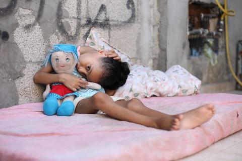 الطفلة سيلا أبو كريم، 6 أعوام، تجلس داخل منزل متضرر في مخيم المغازي وسط قطاع غزة، في 3 سبتمبر/أيلول 2026، بعدما تسببت شظايا غارة إسرائيلية سابقة بإصابات في فقرات ظهرها وعمودها الفقري. تصوير: حسن الجدي.