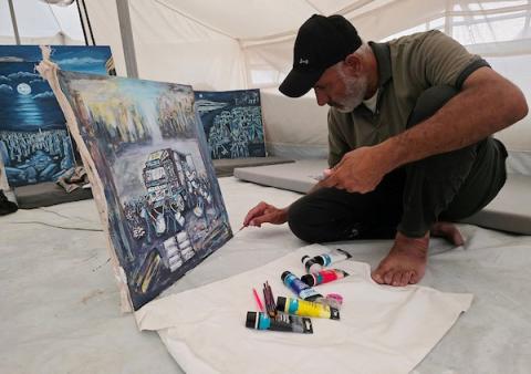 الفنان الفلسطيني جهاد الشرافي يرسم داخل خيمة للنازحين في خان يونس جنوبي قطاع غزة، مشاهد توثق الحرب والجوع ونقص المياه والدمار، في 18 سبتمبر/أيلول 2026.  تصوير: طارق محمد
