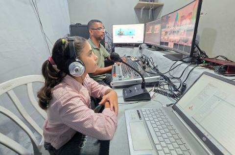 أطفال فلسطينيون يشاركون في إعداد وتقديم برامج لقناة طلائع فلسطين من استوديو متواضع أُقيم داخل خيام النزوح في منطقة مواصي خان يونس. (تصوير: طارق محمد)